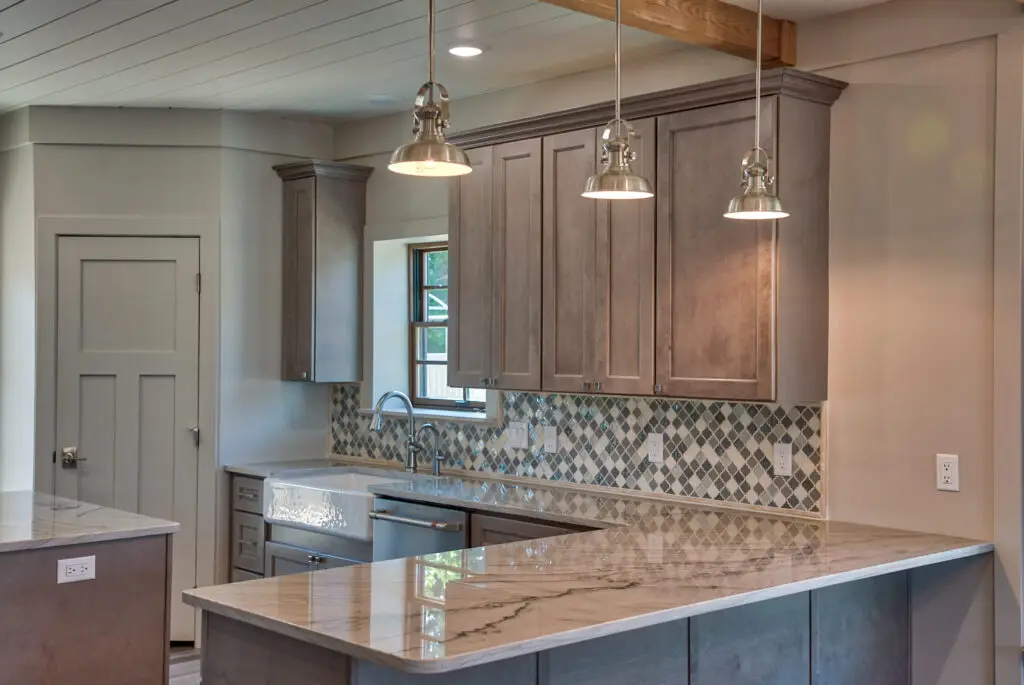 Interior photo of custom-built home by Harvell Homes in Powell, Wyoming featuring a farmhouse kitchen sink, premium appliances, luxury backsplash, and modern farmhouse pendants