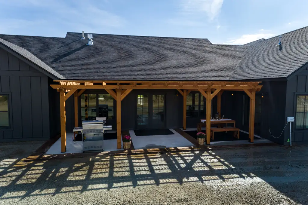 Exterior photo of a one-story modern black home built by Harvell Homes in Powell, Wyoming featuring backyard pergola