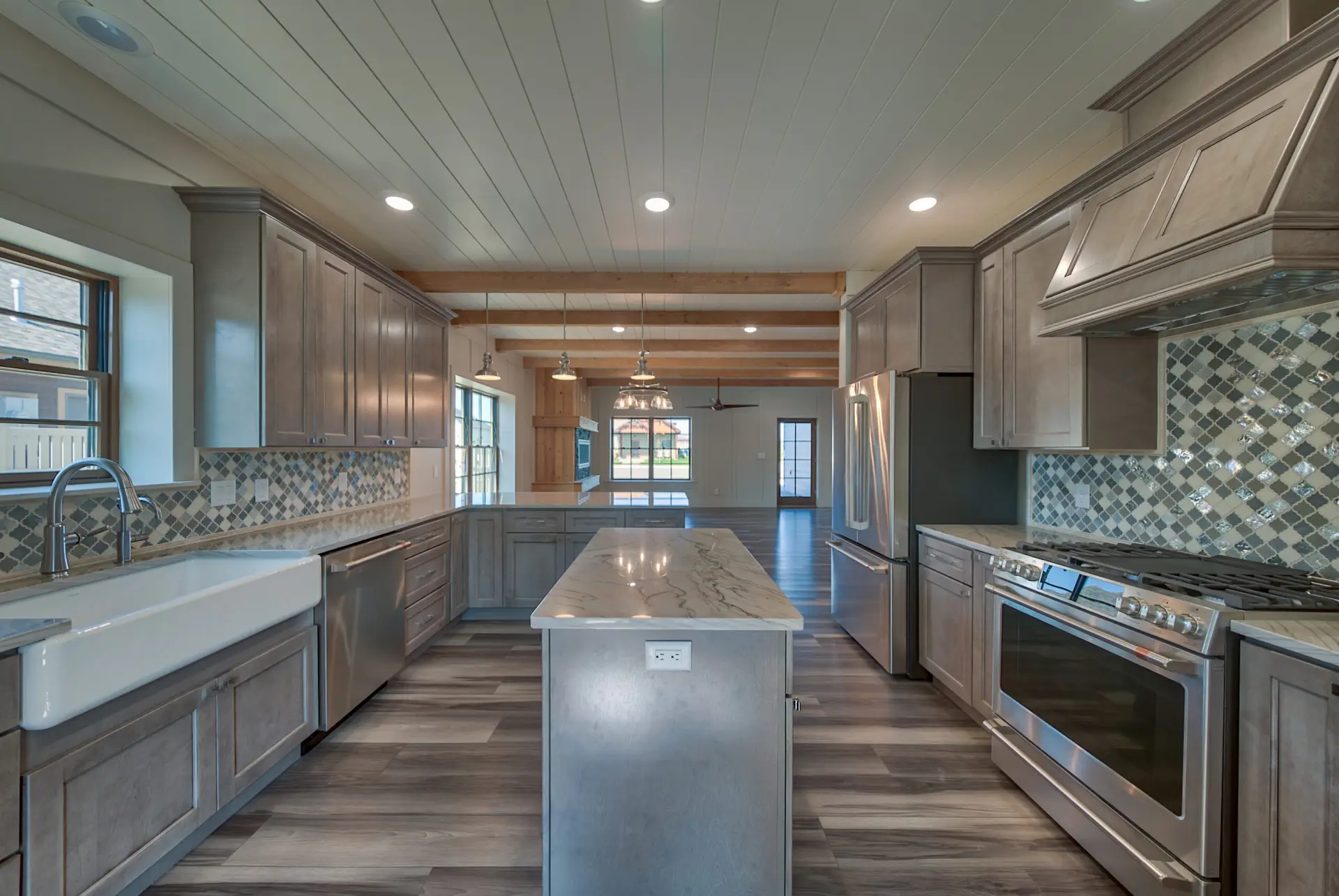 Interior photo of a home built by Harvell Homes in Powell, Wyoming featuring a luxurious custom kitchen with premium appliances, an island, farmhouse kitchen sink and premium backsplash