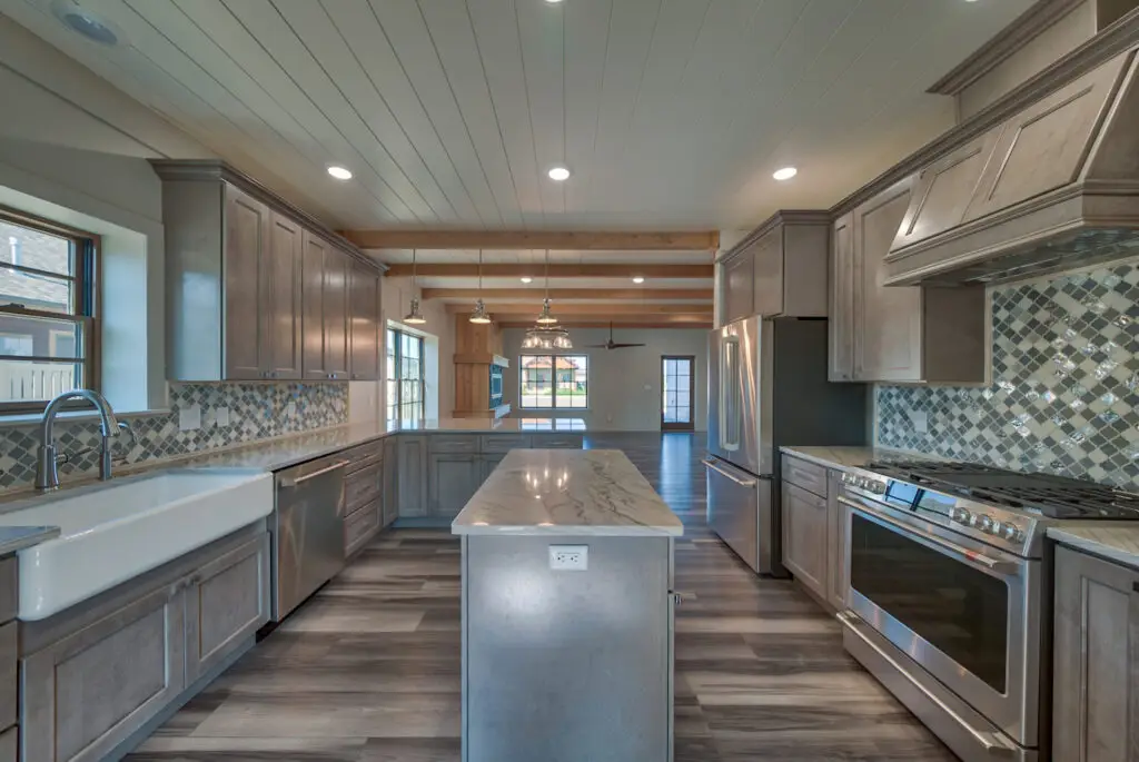 Interior photo of a home built by Harvell Homes in Powell, Wyoming featuring a luxurious custom kitchen with premium appliances, an island, farmhouse kitchen sink and premium backsplash