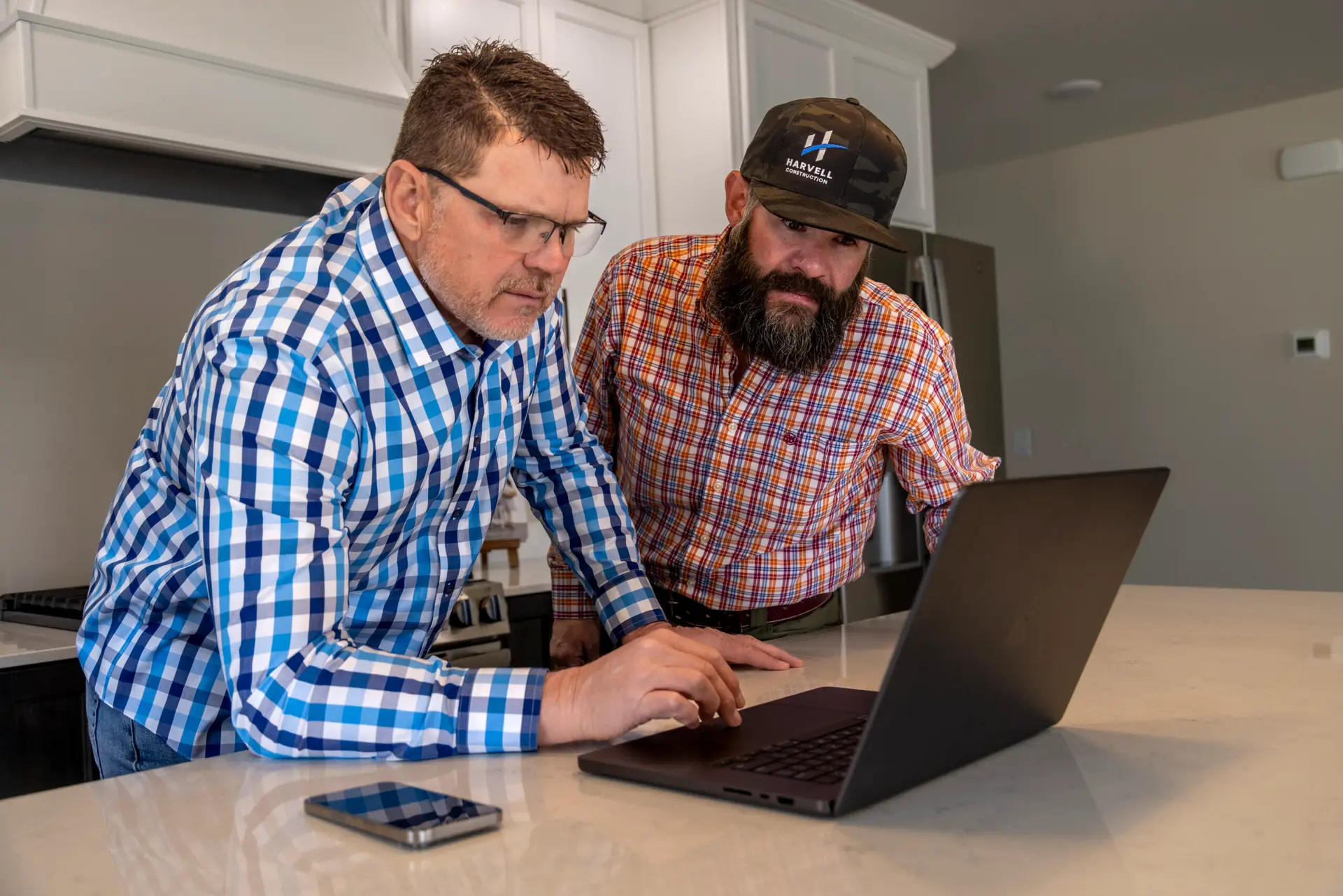 Trent Urwiller, field supervisor, and Chad Harvell of Harvell Homes stands in a custom kitchen designing items together